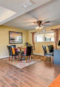 A room with a table, chairs, and a ceiling fan.