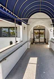 A long, white covered walkway leads to a building entrance.
