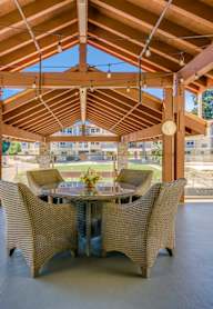 A wooden pergola with a table and chairs is set up outside.
