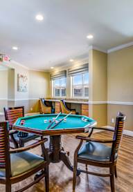 A poker table is surrounded by chairs in a room with a green wall.