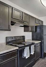 A kitchen with a black refrigerator and stove.