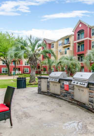 an outdoor patio with a barbecue grill in front of an apartment building