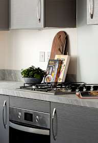 a modern kitchen with grey cabinets and black appliances