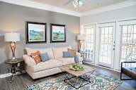A living room with a beige couch, a coffee table, and two framed pictures on the wall.