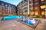 an outdoor pool with water fountains and an apartment building in the background