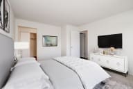 staged bedroom with a bed and a dresser with a television on top of it