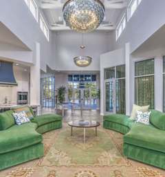 A living room with green couches and a large chandelier.