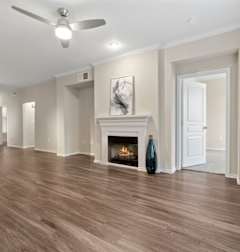 A spacious room with a fireplace and wood flooring.