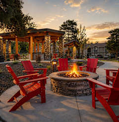 A fire pit surrounded by red chairs in a backyard setting.
