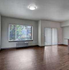 A room with a window showing a view of a building and trees outside.