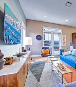 A living room with a blue couch and a wooden cabinet.