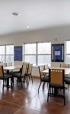 A room with a long table and chairs with a sign on the wall.