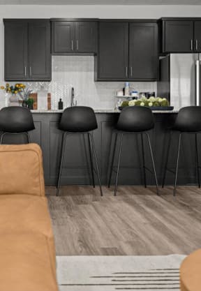 a living room with a couch and a kitchen with black cabinets