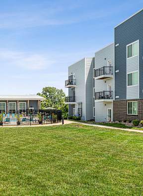 A grassy area in front of apartment buildings with a playground.
