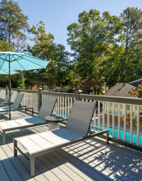 a large deck with lounge chairs and umbrellas at Elme Cumberland Apartments, Smyrna, GA, 30080