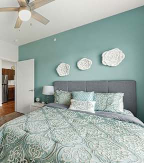 A bedroom with a bed, dresser, and ceiling fan.