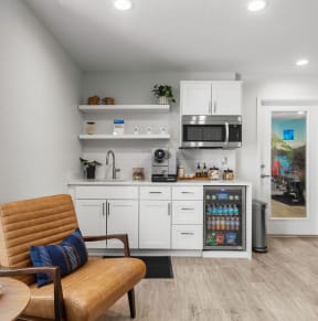 a living room with a chair and a kitchen with a microwave