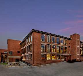 A large red brick building with a parking lot in front.