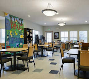 A room with tables and chairs and a sign that says Reduce, Reuse, Recycle.