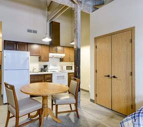 A kitchen with a table and chairs in the foreground and a refrigerator in the background.