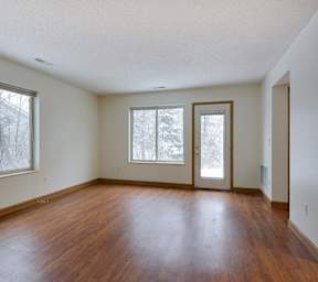 Empty room with wood floors and three windows.