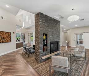 A modern living room with a stone fireplace and wooden floors.