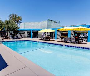 A pool with a blue tiled edge and yellow umbrellas.