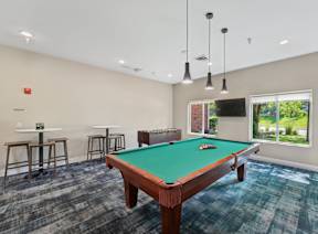 A pool table is in the middle of a room with a green cloth on it.