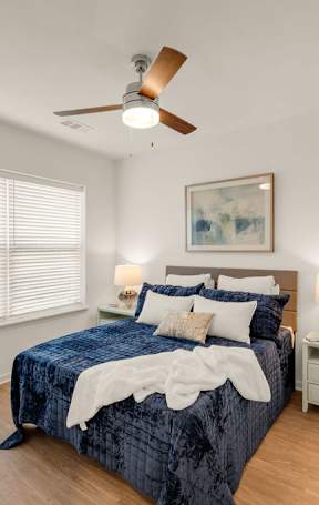 A bedroom with a bed, nightstand, and a ceiling fan.