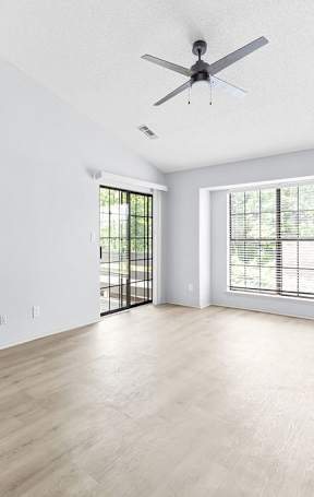 A spacious room with a ceiling fan and sliding glass doors.