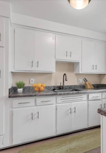 A kitchen with white cabinets and a marble countertop.