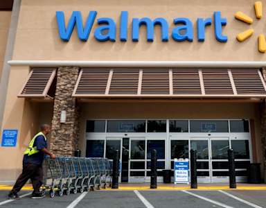 A Walmart store entrance with a person pushing a shopping cart.