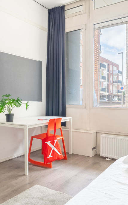 A bedroom with a bed, desk, and chair.