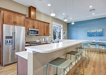 A kitchen with a white counter and green stools.