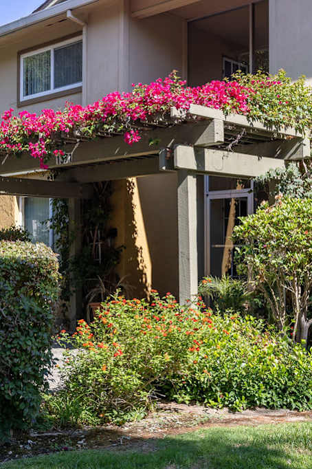 the front entrance of an apartment building with pink flowers on a porch