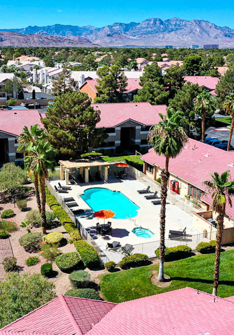 A tennis court is surrounded by houses with red roofs.