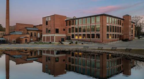 A large building with a reflection in the water in front of it.