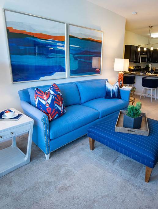 A blue couch with a wooden tray on top of a blue carpet.