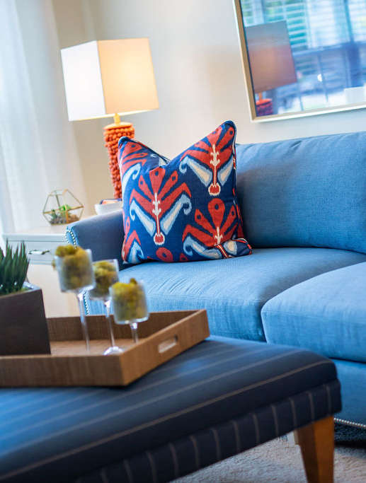 A blue couch with a wooden tray on top of a coffee table.