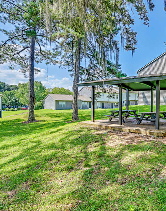 A picnic table is situated under a pavilion in a grassy area.