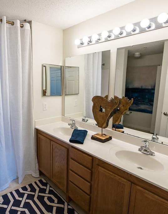 A bathroom with a white sink, a mirror, a shower, and a moose head.