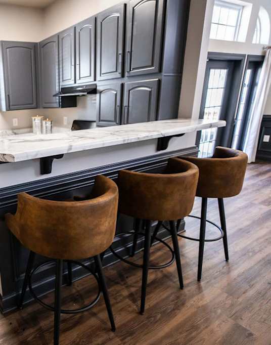A kitchen with black cabinets and a white island.