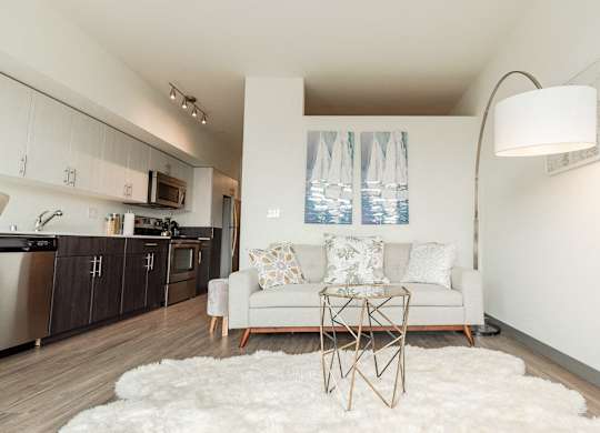 Apartments in Seattle, WA - Icon Apartments Modern Living Room Next to Kitchen with Hardwood Flooring and Natural Light at Icon Apartments, Washington
