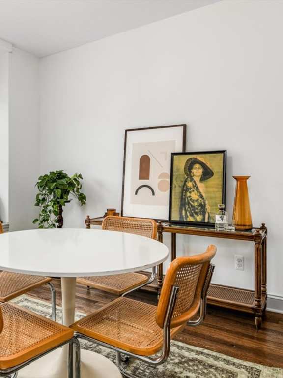 A white table with four chairs in front of a window.