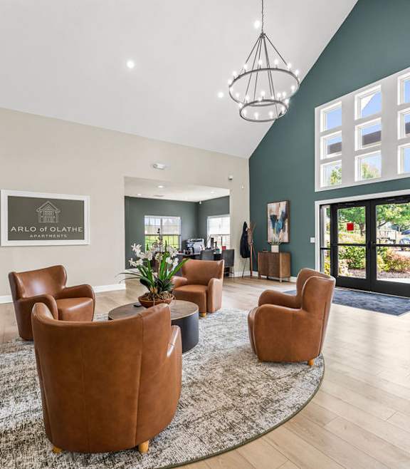 A living room with a rug, chairs, and a painting on the wall.