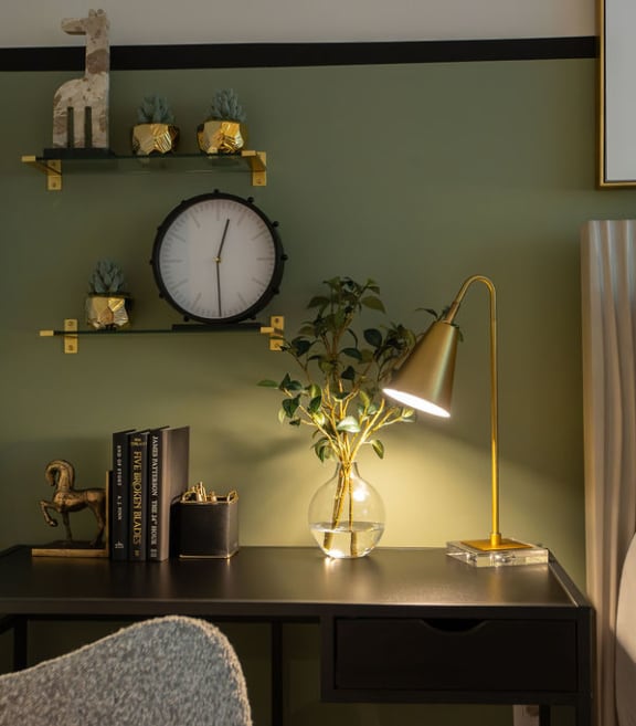 a bedroom with a desk with a lamp and a clock on the wall