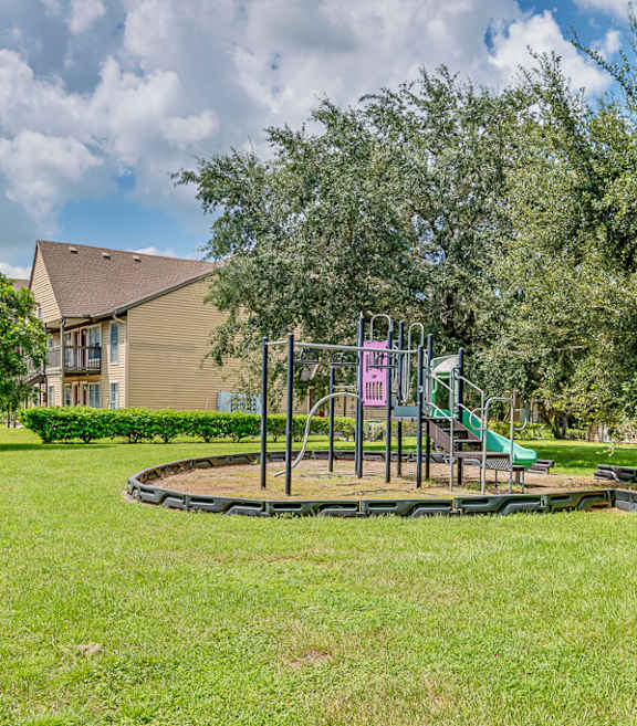 A playground with a slide and swings in a grassy area.