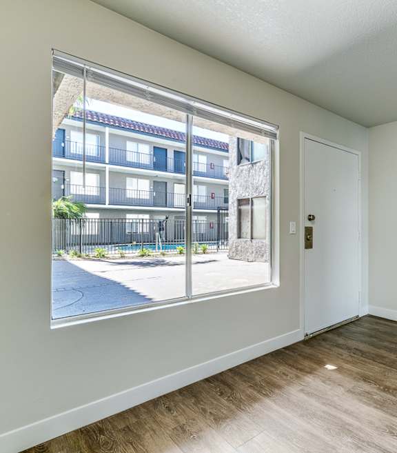 an empty living room with a large window and wood flooring