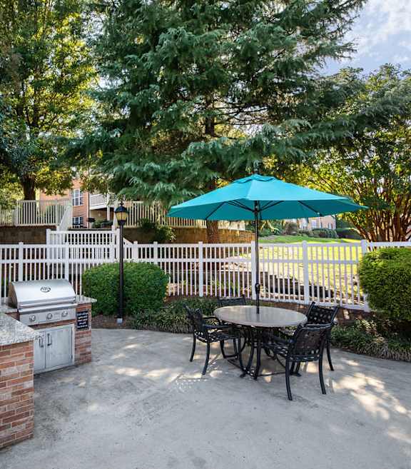 A patio with a table and chairs and an umbrella.