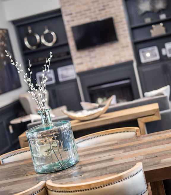 A glass vase with branches in it sits on a wooden table.